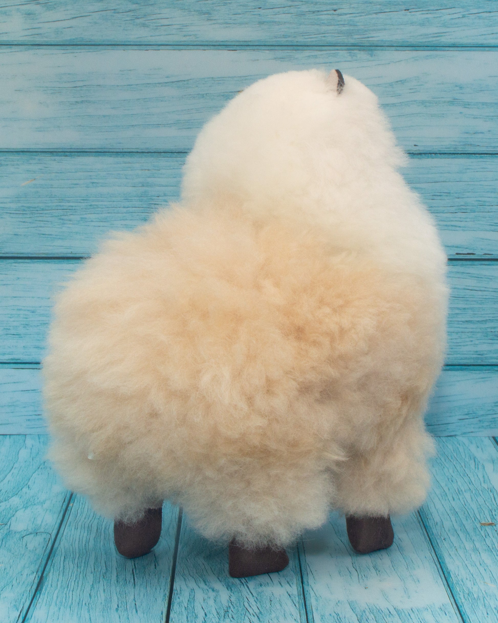 Soft alpaca stuffed animal. Beige and white, 9 inches. Back view